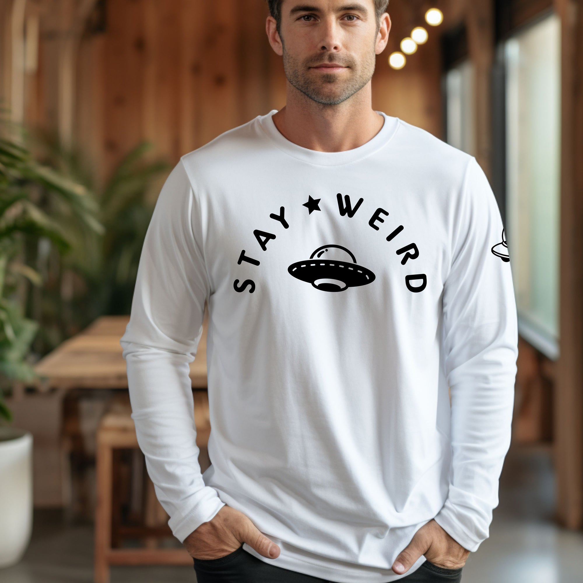 A male model wearing the white Stay Weird UFO long sleeve tee, showcasing the regular fit and chest graphic.