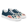 A pair of women's Orca Snork canvas sneakers are shown from a right-angled view against a white background. The shoes have a dark navy blue upper and a cream-colored lower section with a pink and blue floral pattern. The white laces and soles provide a sharp contrast.