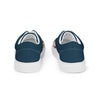 A pair of women's Orca Snork canvas sneakers are shown from a back-facing product shot. The shoes have a solid dark navy blue heel and a white sole. The left shoe is angled slightly inward, and a glimpse of the pink and blue floral pattern is visible on the side of the right shoe.