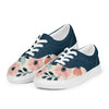A pair of women's Orca Snork canvas sneakers, featuring a navy blue and floral pattern, are shown from a left-side product shot. The shoes have a dark navy blue upper and a cream-colored lower with a pink and blue floral design. The white laces and soles provide a sharp contrast.