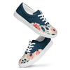 A pair of women's Orca Snork canvas sneakers, featuring a navy blue and floral pattern, are shown in a product shot. The shoes have a dark navy blue upper and a cream-colored lower with a pink and blue floral design. The white laces and soles provide a sharp contrast.