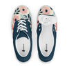 A top-down product shot of a pair of women's Orca Snork canvas sneakers against a white background. The left shoe's interior and logo on the insole are visible. The right shoe is angled to reveal the size tag inside the tongue. The shoes have a dark navy blue section around the laces and a cream-colored toe and side panel with a pink and blue floral pattern. White laces and soles provide a sharp contrast.