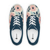 A pair of women's Orca Snork canvas sneakers are shown from a top-down view against a white background. The shoes have a dark navy blue section around the laces and a cream-colored toe and side panel with a pink and blue floral pattern. The white laces are clearly visible, as are the inner soles with the "ORCASNORK.COM" logo.