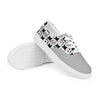 A pair of Orca Snork Playful One-Eyed Cat Canvas Sneakers, propped up on a white background to show the textured rubber outsole and the vibrant pattern of our one-eyed feline, Orca, along with paw prints, hearts, fishbones, and blue fish.